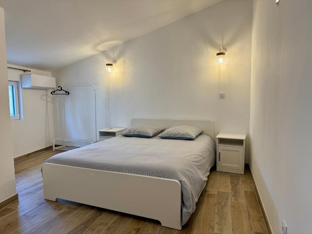 a bedroom with a white bed and two night stands at Maisonnette de village à Rasteau in Rasteau