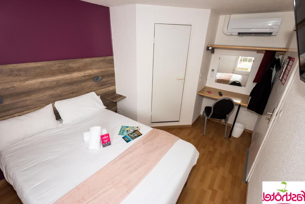 1 dormitorio con cama blanca y escritorio con silla en Fasthôtel - Un hôtel FH Confort, en Limoges