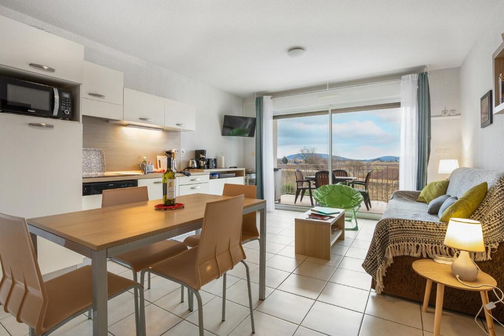 une cuisine et un salon avec une table et des chaises dans l'établissement Jakine - Joli T2 avec terrasse, à Azille