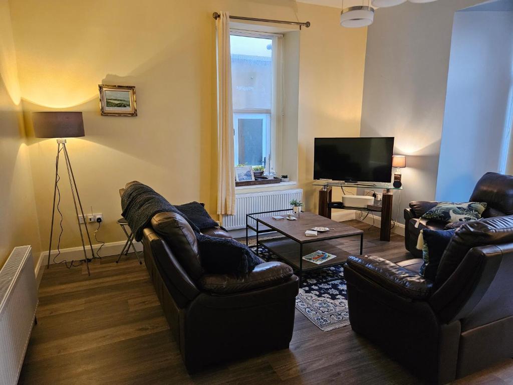 a living room with couches and a flat screen tv at Atlantic Views ground floor apartment in Portrush
