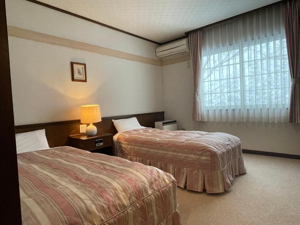a hotel room with two beds and a window at マウンテンリゾート・マルガンタ Marganta in Madarao Kogen