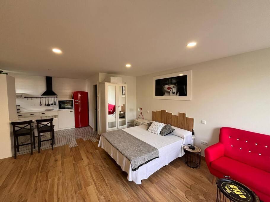 een slaapkamer met een bed en een rode bank bij Estudio Bolingas in Comillas