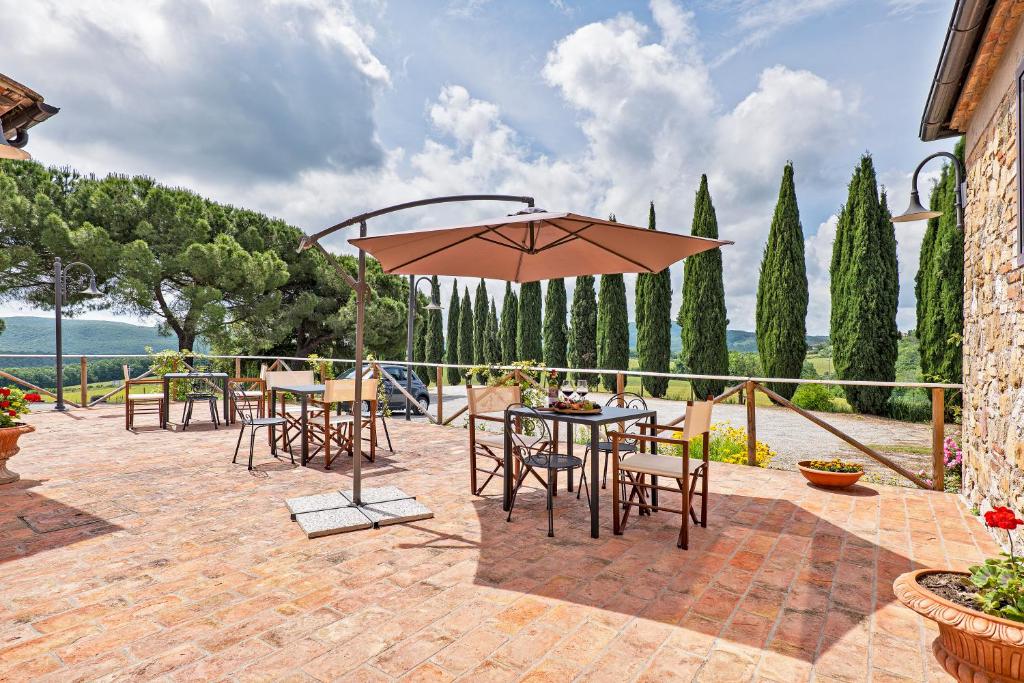 taras ze stołami, krzesłami i parasolem w obiekcie Casalchino-Fattoria La Torre w mieście San Gimignano
