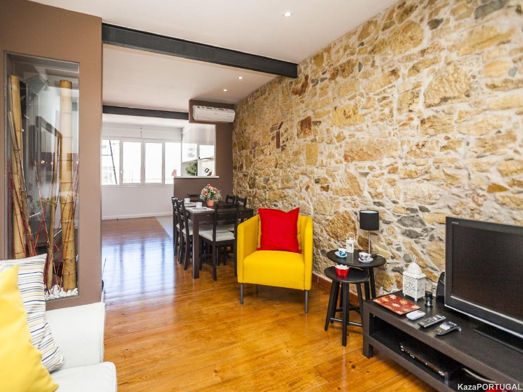 a living room with a yellow chair and a stone wall at Calado Apartments in Lisbon