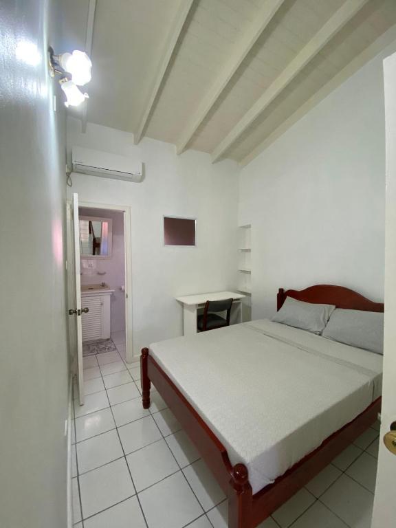 Thrillers Apartments في Gwa Kay: غرفة نوم بيضاء مع سرير وطاولة