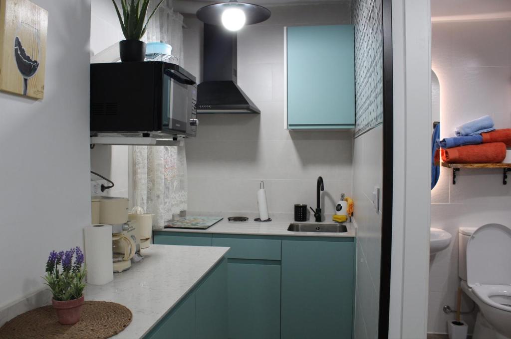 uma pequena cozinha com armários azuis e um lavatório em El Rincón de la Azucena em Guadalajara