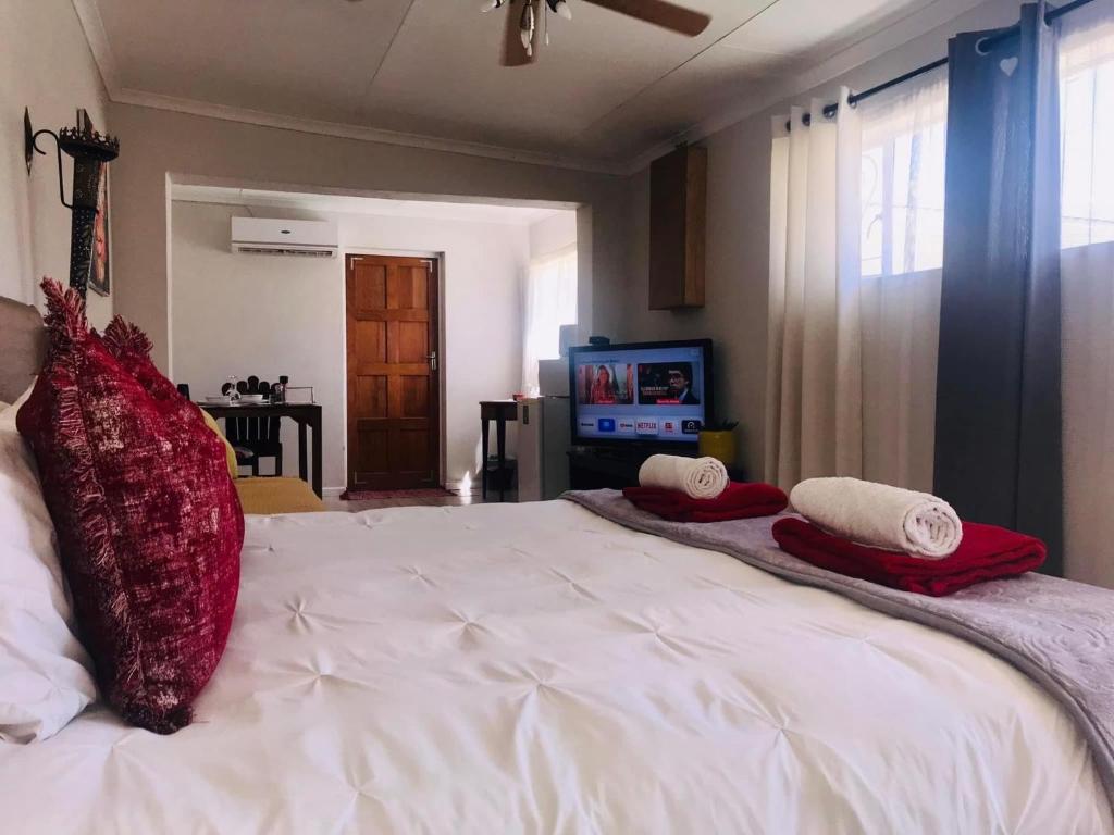 1 dormitorio con 1 cama blanca grande con almohadas rojas en Toni's Cottage, en Graaff-Reinet