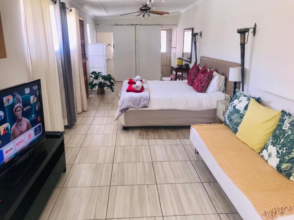 a bedroom with a bed and a tv and a couch at Toni's Cottage in Graaff-Reinet