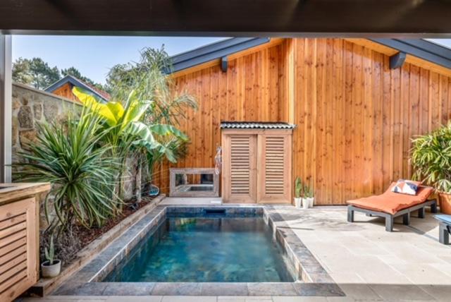 ein Schwimmbad vor einem Holzgebäude in der Unterkunft La Cabane du Huga N°2 in Lacanau