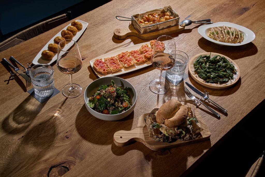 a wooden table topped with plates of food and wine glasses at Sant Jaume Design Hotel in Palma de Mallorca