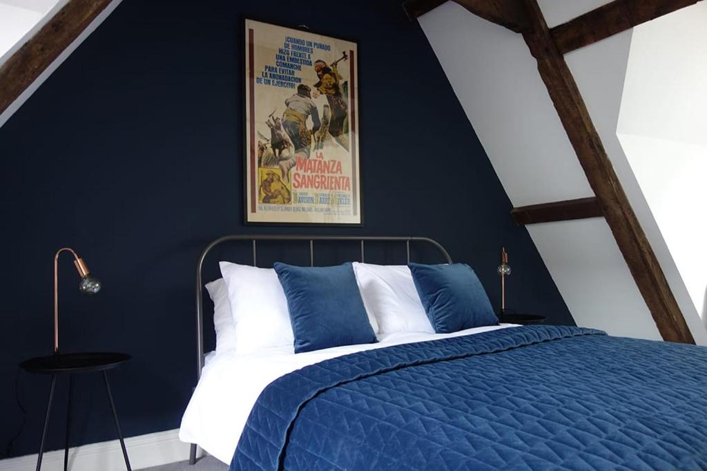 ein blaues Schlafzimmer mit einem Bett und einem Plakat an der Wand in der Unterkunft Grade II Listed Flint Cottage Sleeps 4 in Norwich