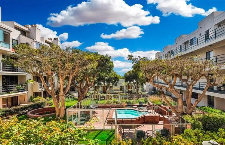 an apartment complex with a swimming pool and trees at Santa Monica Beach Amazing 2 Bedroom Condo in Los Angeles