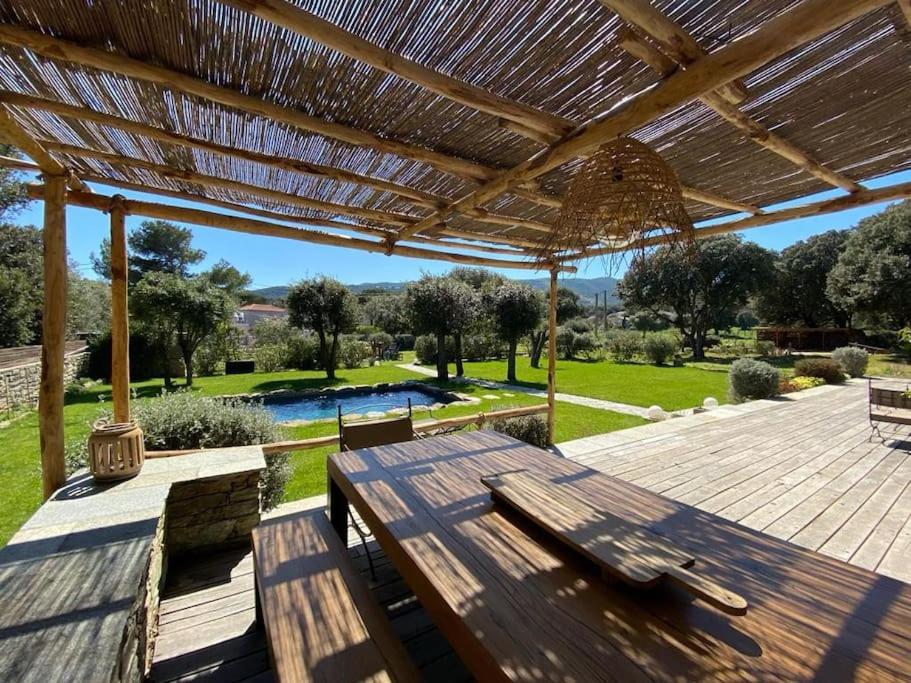 une pergola en bois avec une table et des bancs sur une terrasse dans l'établissement Bergerie du Cap Corse, à Macinaggio