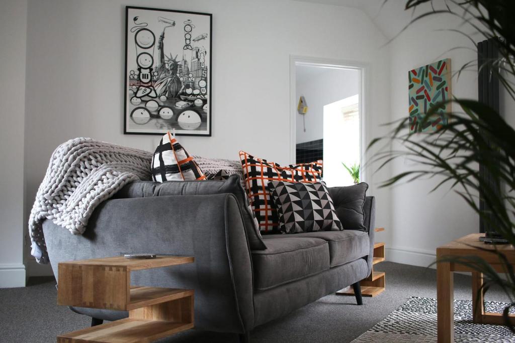 uma sala de estar com um sofá cinzento com almofadas em No. 82 Grade II Listed Norwich City Centre Flat em Norwich