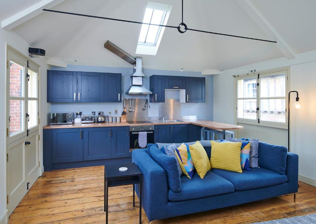 a living room with a blue couch and a kitchen at Studio 2 - Central Location Sleeps 4 in Norwich