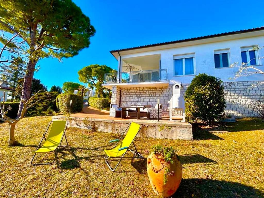 a group of yellow chairs in front of a house at Villa Renata, bellissima villa con terrazzo vista mare e spiaggia inclusa in Numana