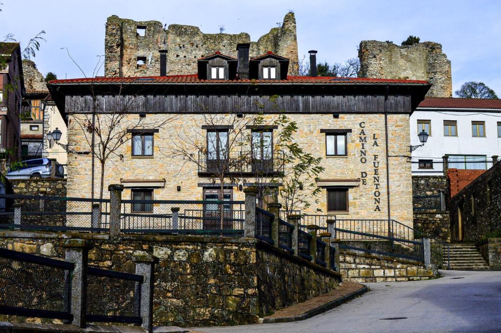 um antigo edifício de pedra com um castelo ao fundo em C.T.R. Camino de la Fuentona em Cabrejas del Pinar