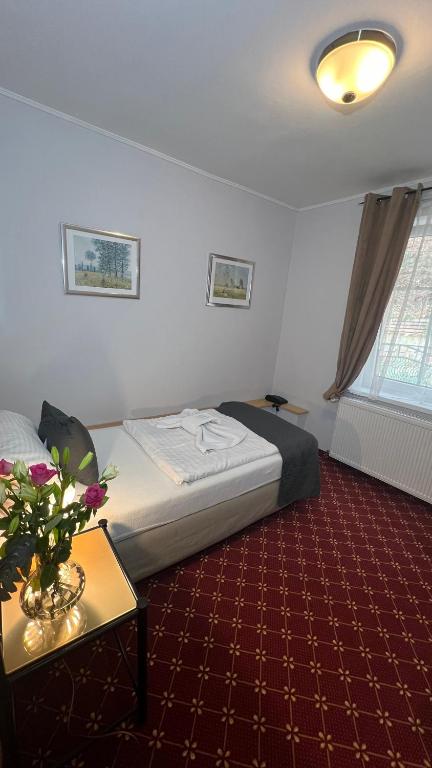 a hotel room with a bed and a table with flowers at Hotel Boston in Karlovy Vary