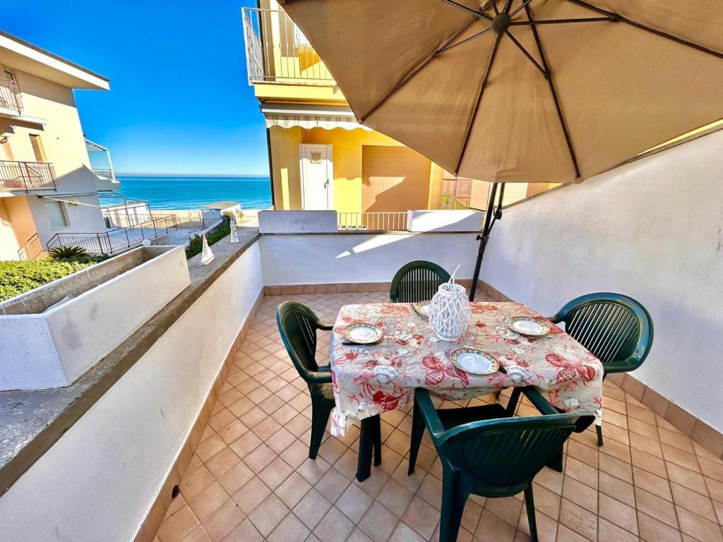 マルチェッリにあるMARZIO - appartamenti con terrazzo, posto auto e spiaggiaのテーブルと椅子、バルコニー(パラソル付)