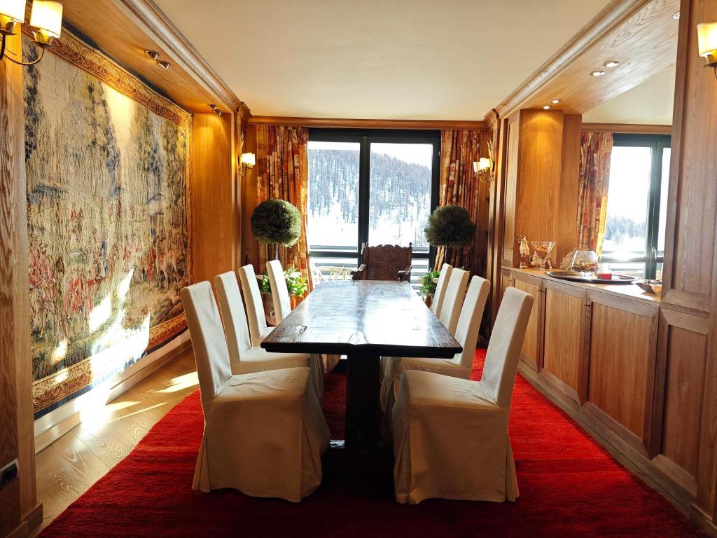 a dining room with a table and white chairs at Hostdomus - 007 Luxury Suites in Sestriere