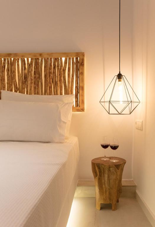 a bedroom with a bed and two glasses of wine at Casa Centro Suites Mykonos in Mikonos