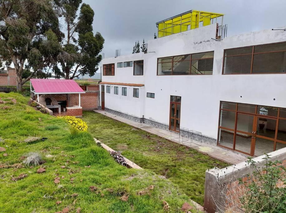 un edificio blanco con techo rojo y banco en Casa Ymelda, en Desaguadero