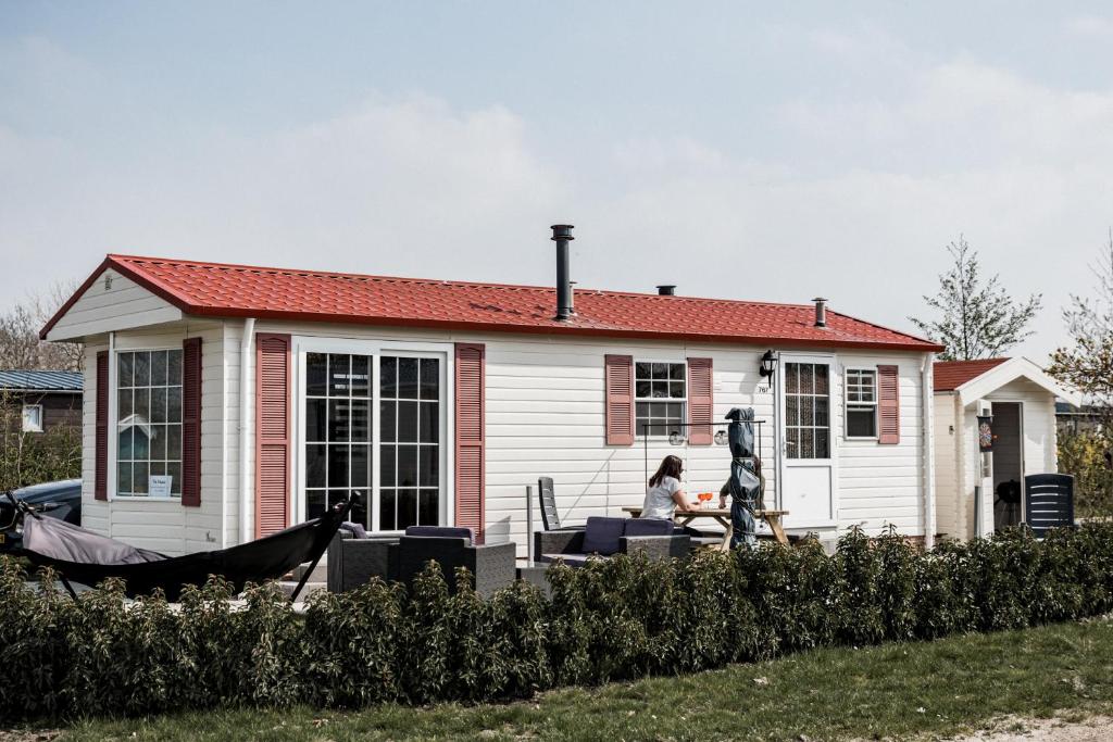 uma mulher sentada em frente a uma casa em Chalet Zeeuws Genieten in Baarland, Zeeland em Baarland