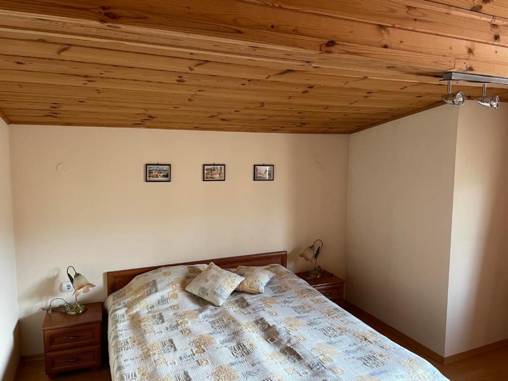 a bedroom with a bed and a wooden ceiling at Kalaidjievi in Bansko
