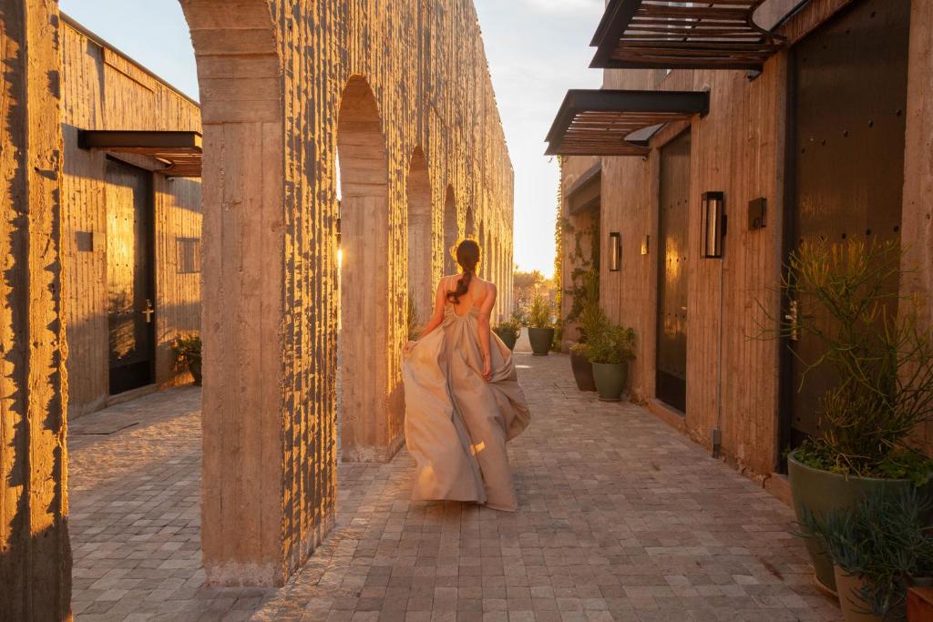 Une femme en robe marchant dans une rue dans l'établissement Hotel Andana Winery & Spa, à Valle de Guadalupe