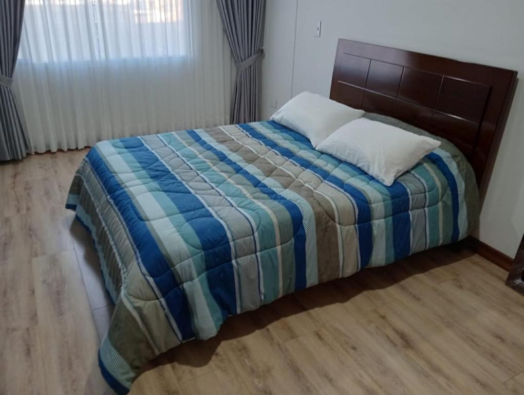 a bedroom with a bed with a blue and striped blanket at descanso los ANDES in Duitama