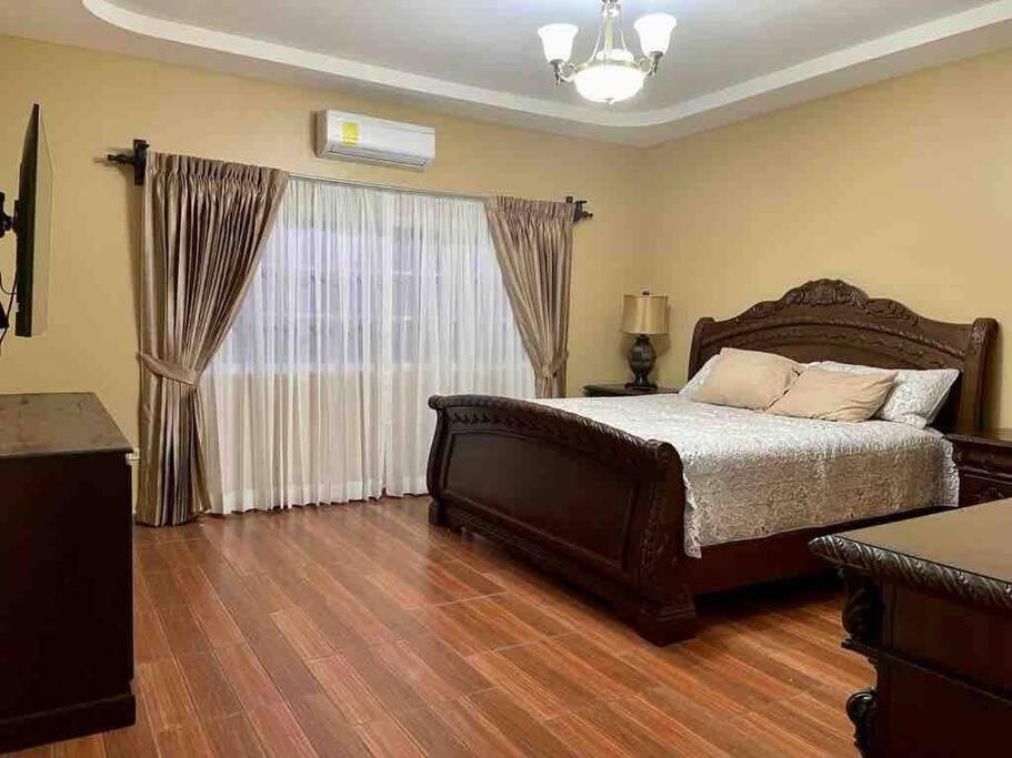 um quarto com uma cama grande e uma janela grande em Casa del Ángel - Cerca de la Embajada Americana em Tegucigalpa