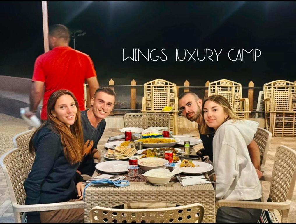 a group of people sitting at a table eating food at WADI RUM WINGS lUXURY CAMP in Wadi Rum
