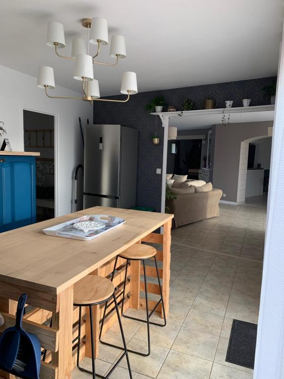 a kitchen with a wooden table with two stools at Gite de Groupe Aux Instants Partagés in Fontenay-sur-Vègre