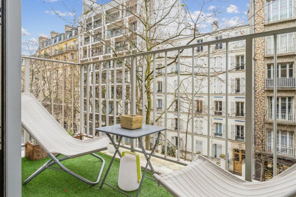 balkon z 2 krzesłami i stołem oraz budynek w obiekcie Spacious apartment with balcony in Paris - Welkeys w Paryżu