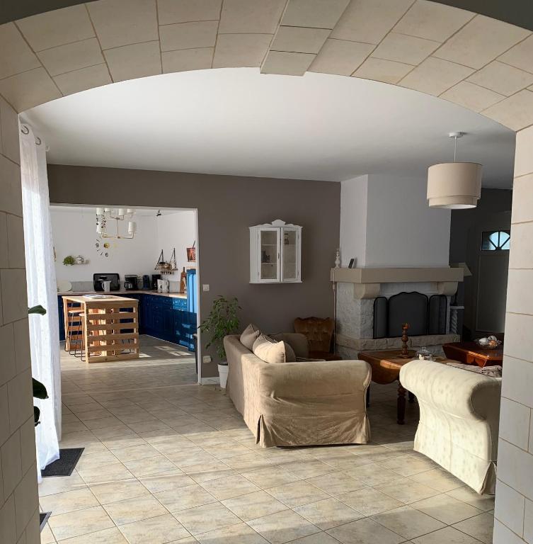 a living room with two couches and a kitchen at Gite de Groupe Aux Instants Partagés in Fontenay-sur-Vègre