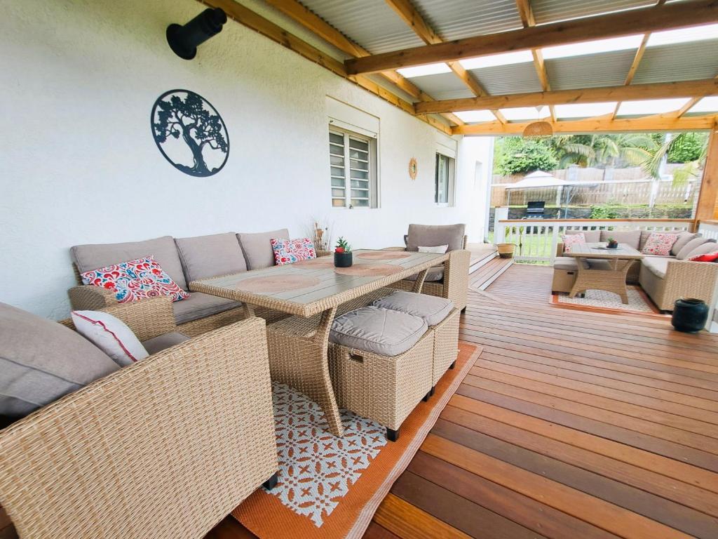 eine Terrasse mit einem Sofa und einem Tisch auf einer Terrasse in der Unterkunft La Villa Camael in Le Tampon
