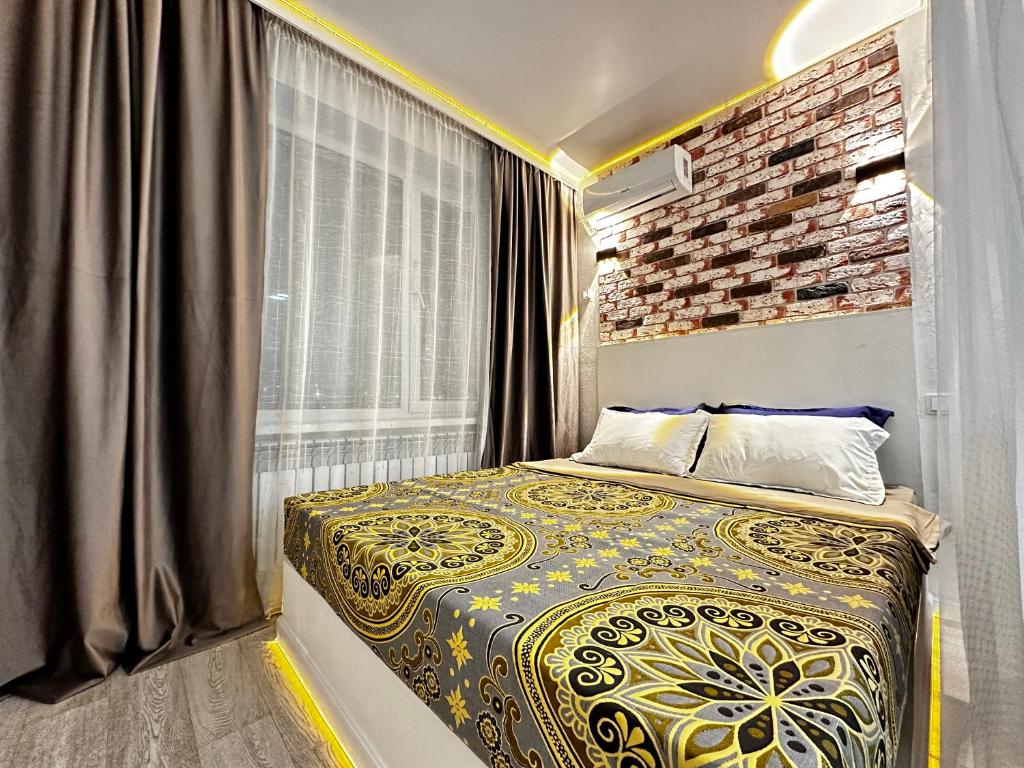 1 dormitorio con cama y pared de ladrillo en «Созвездие Auezov City: Уютные апартаменты в Сердце города», en Almaty