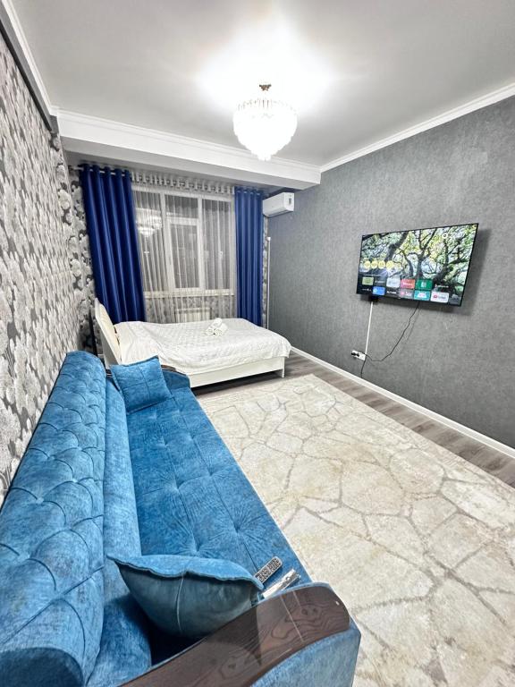 een woonkamer met een blauwe bank en een bed bij Goktash in Bisjkek