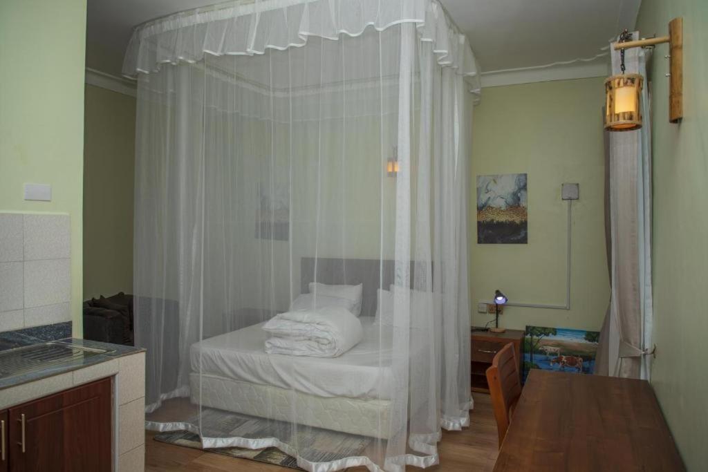 1 dormitorio con 1 cama con cortinas blancas en MT. Rwenzori Golf Resort & Spa, en Rubona