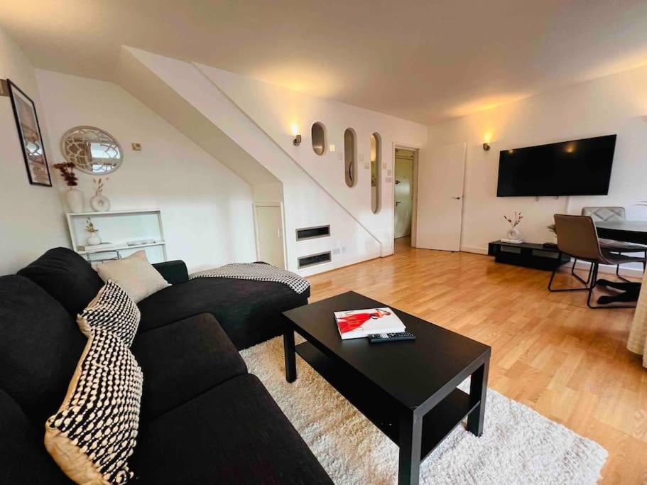 een woonkamer met een zwarte bank en een tafel bij 2 Bed Apartment- Central London in Londen