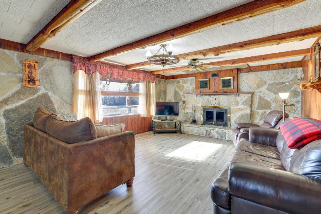 un soggiorno con mobili in pelle e camino in pietra di Authentic Log Cabin in Pineville about 2 Mi to River! 
