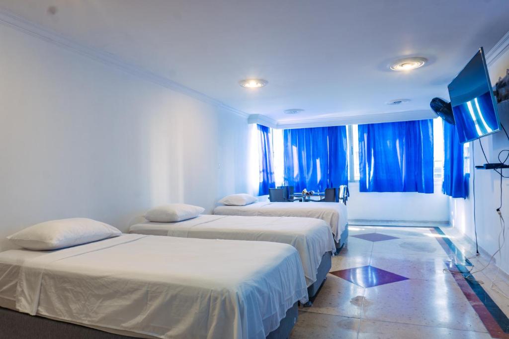 drie bedden in een kamer met blauwe verlichting bij Acogedor Loft Laguito 1 Habitacion N in Cartagena