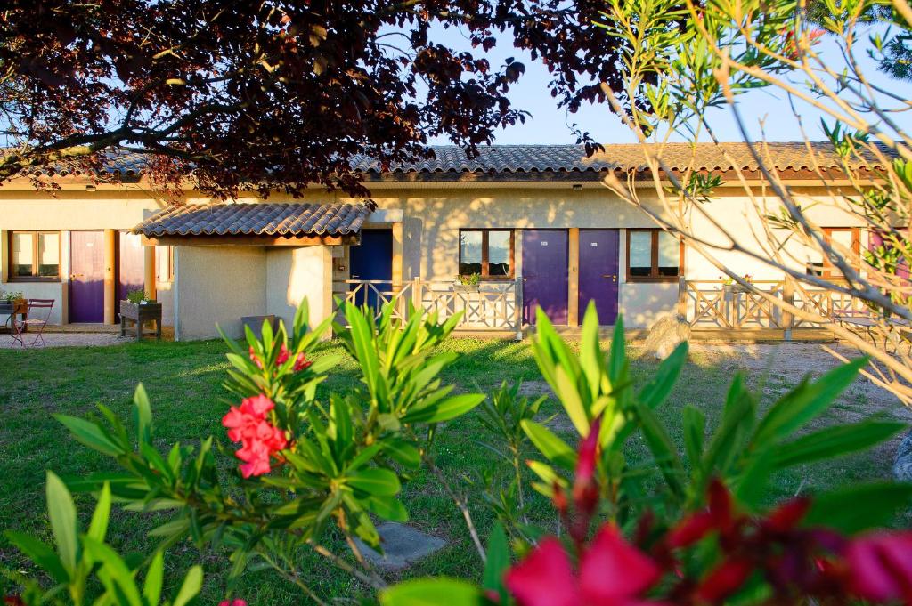 una casa con puertas moradas y flores en el patio en Logis Le Mistral - Montélimar Sud, en Châteauneuf-du-Rhône