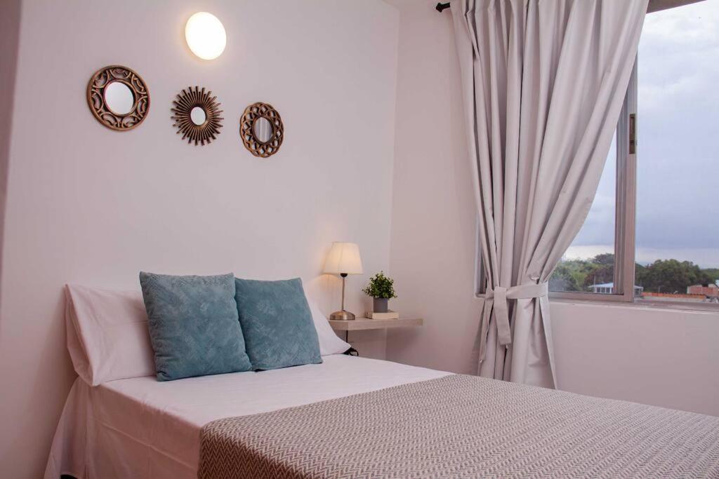 - une chambre blanche avec un lit et une fenêtre dans l'établissement Acogedor Apartamento en Buga, à Buga