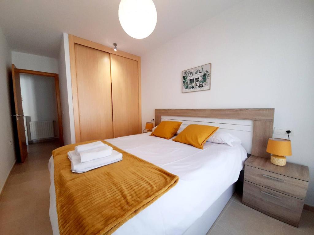 1 dormitorio con 1 cama blanca grande con almohadas amarillas en Apartamento Lita, en Posada de Llanes