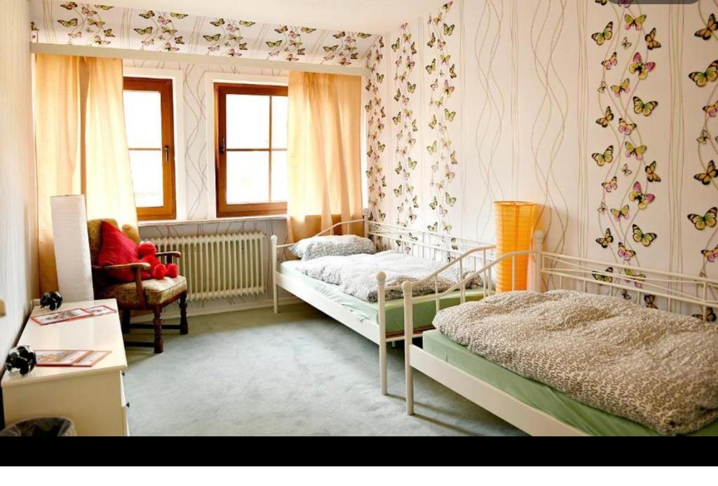 een slaapkamer met 2 bedden, een stoel en ramen bij Hotel am Naturschutzpark in Undeloh
