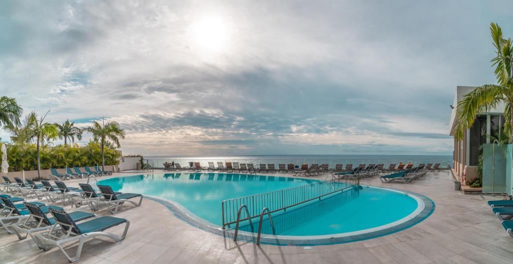 een zwembad met stoelen en de oceaan op de achtergrond bij Duas Torres View Apartment in Funchal