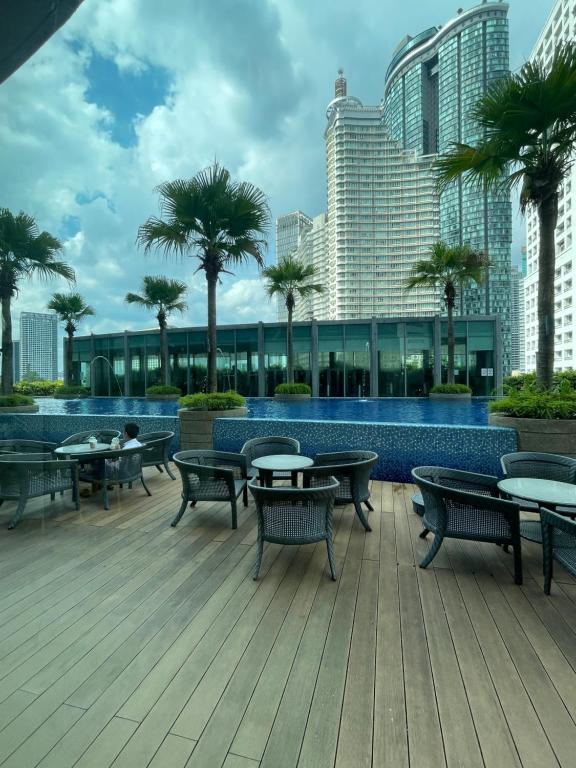 a deck with tables and chairs and palm trees at Vortex Suites KLCC By Paradise IN Kuallampur City in Kuala Lumpur