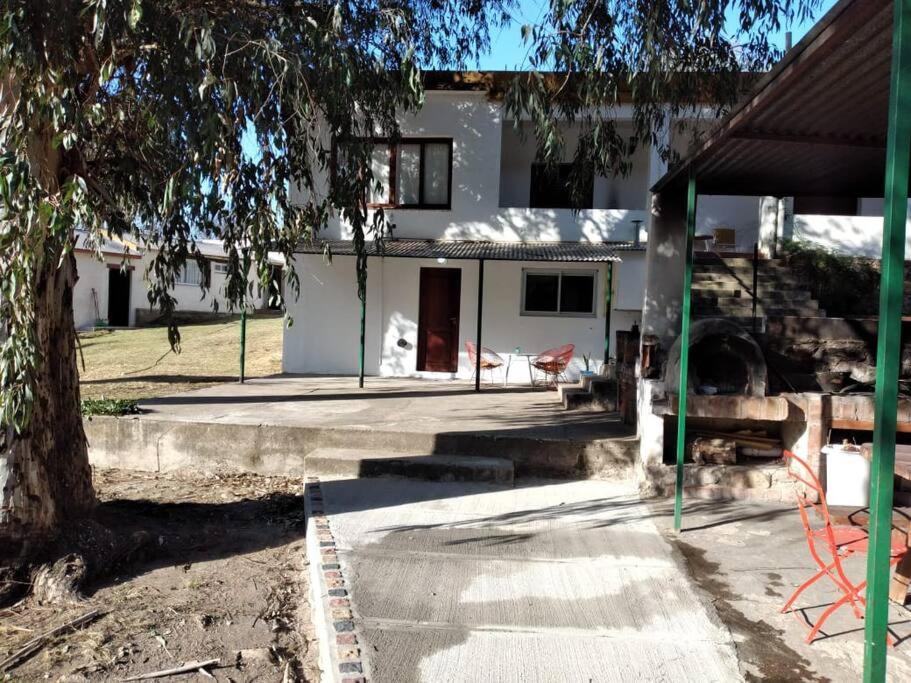 a white house with a tree in front of it at Alojamiento frente al Arroyo Cristal in Tanti