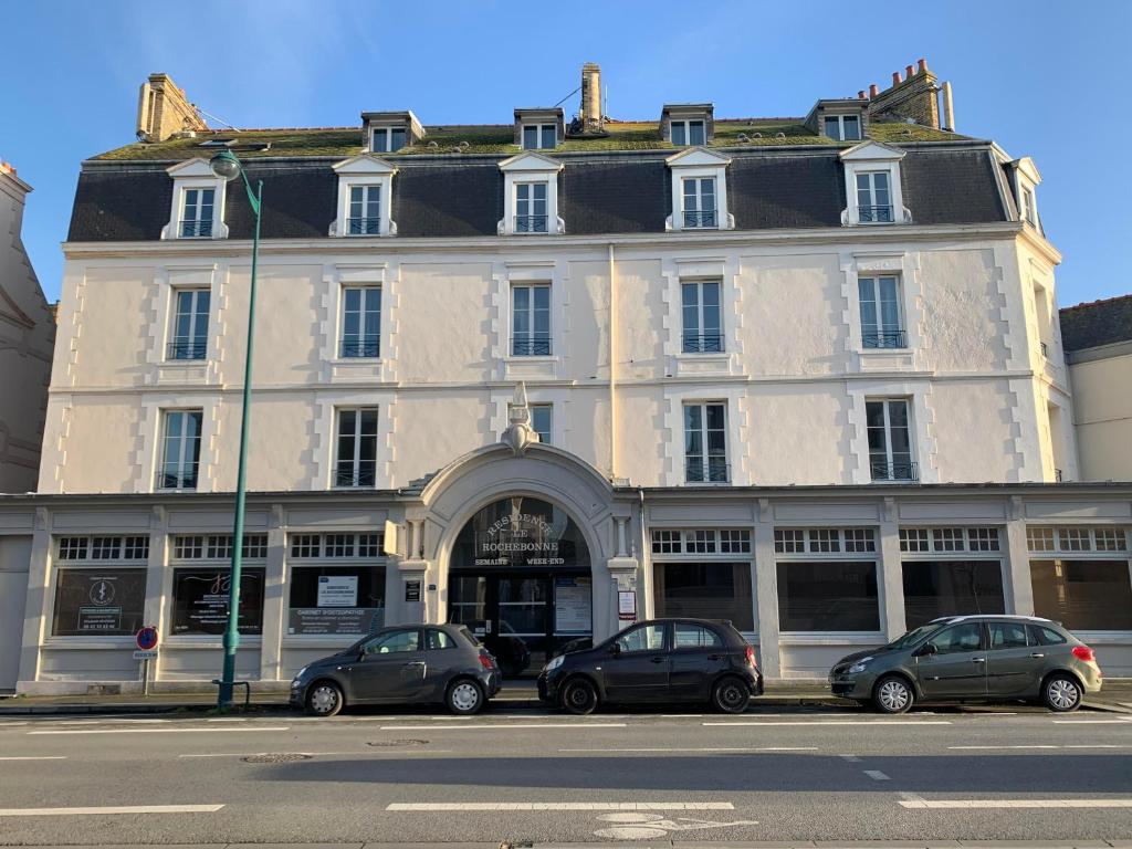 un gran edificio blanco con coches estacionados frente a él en Résidence Le Rochebonne, en Saint-Malo